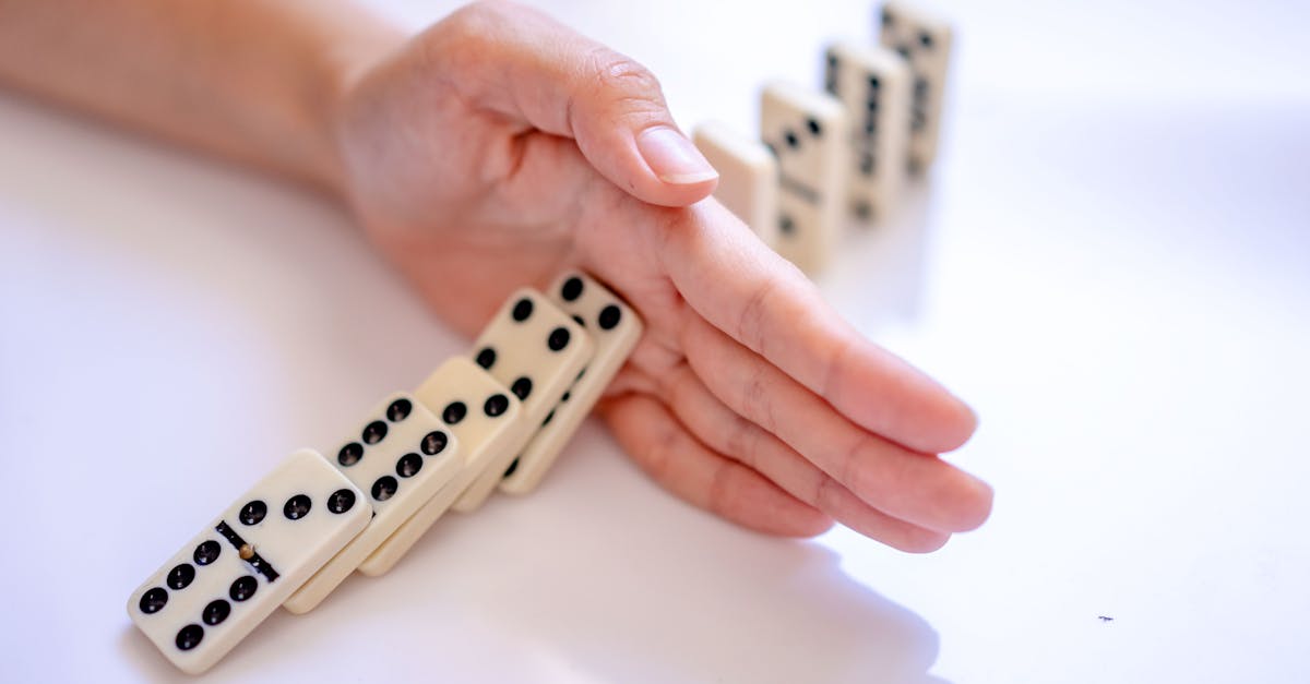 A hand stopping the domino effect, captured on a white background, symbolizing control.